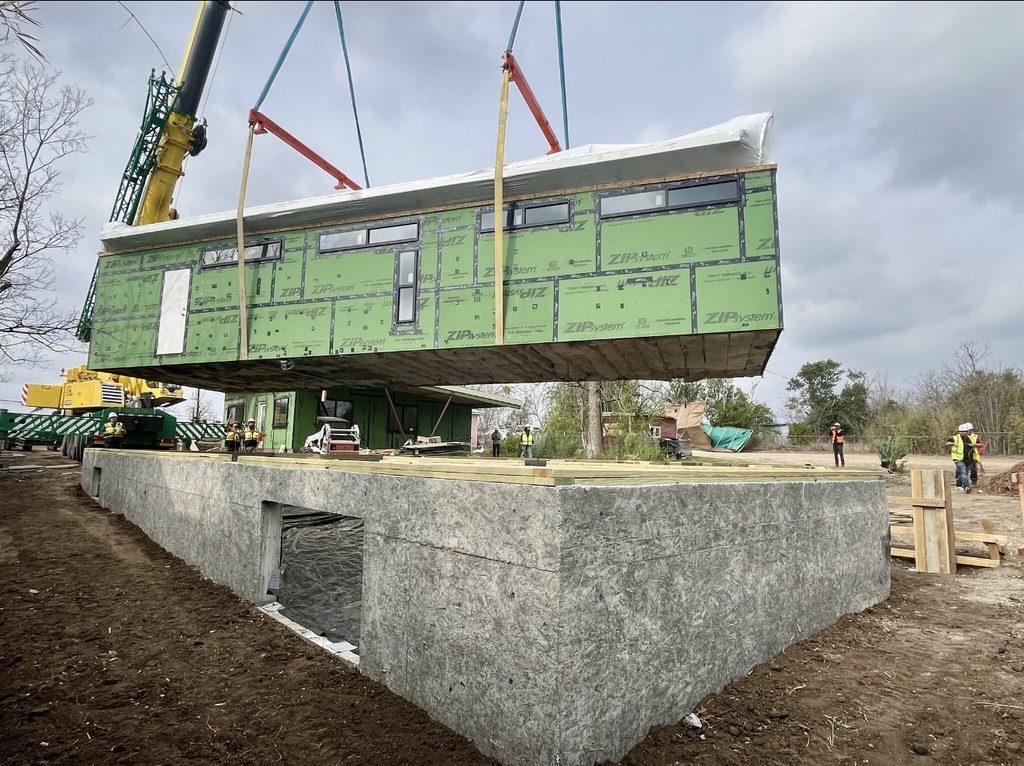 Crane setting a modular building module onto its foundation